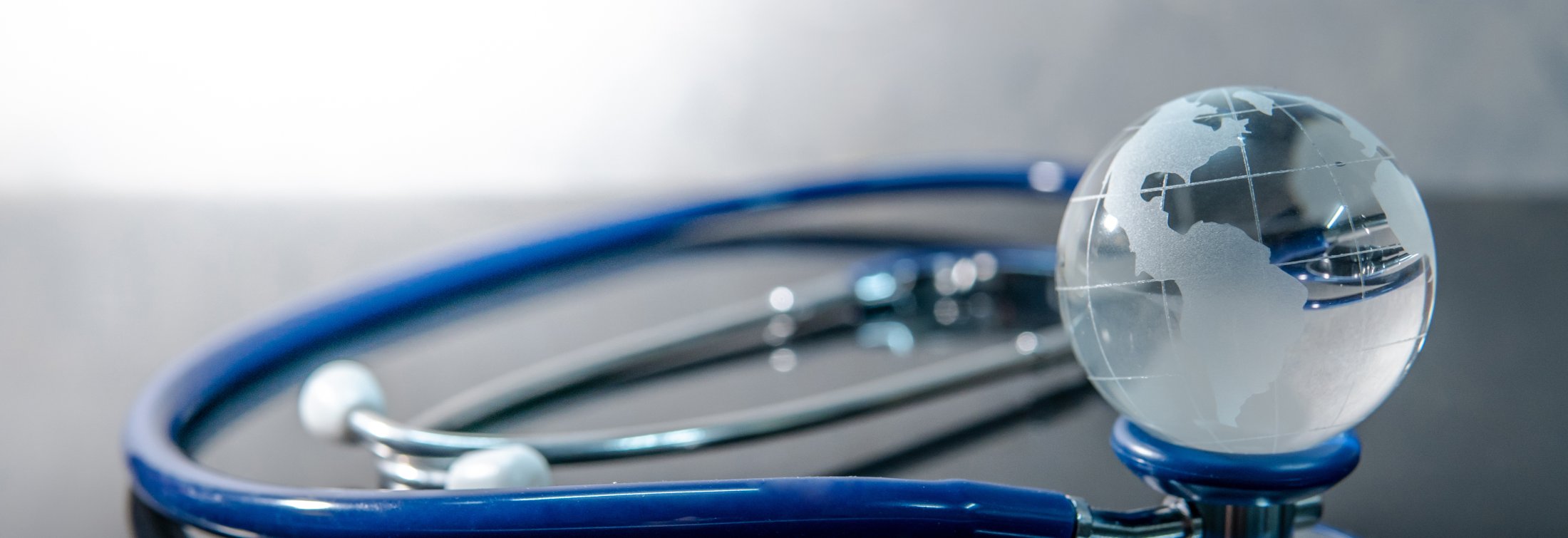 World globe crystal glass on blue stethoscope on glossy desk.