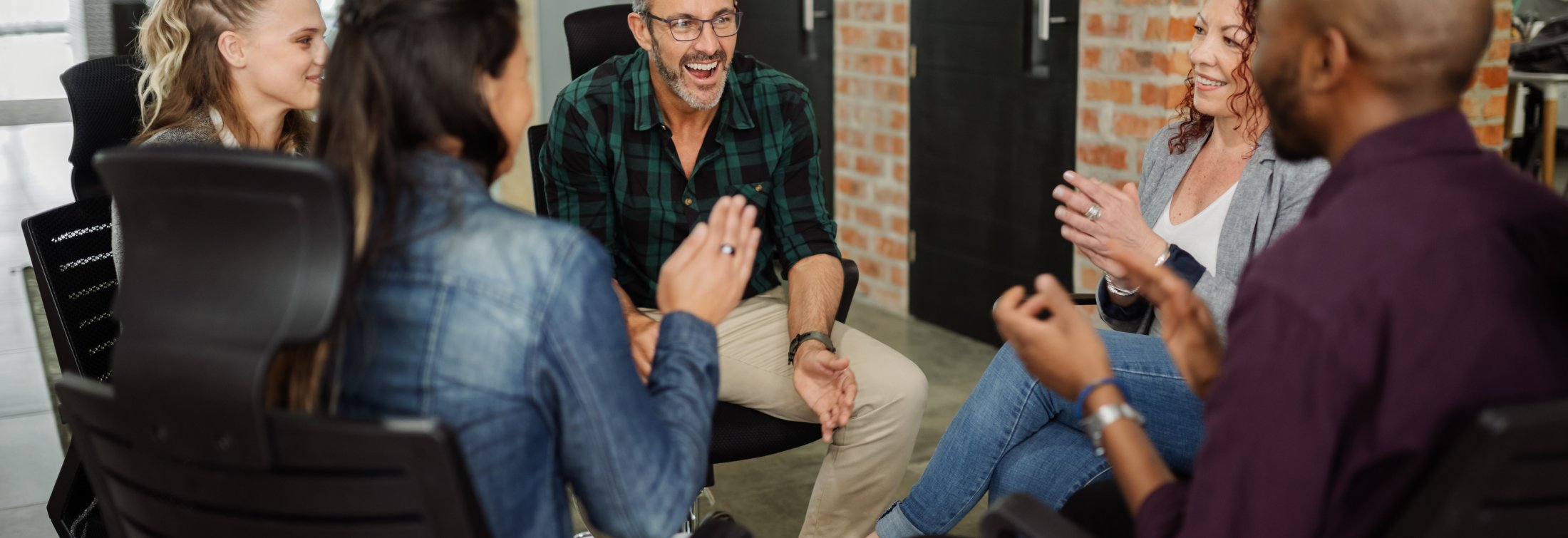 Diverse group of business people sitting in circle. Handsome man talking with coworkers in a team building session.